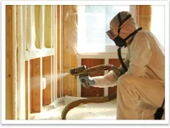 Spray foam insulation being installed in an unfinished wall by a technician wearing a hazmat suit.