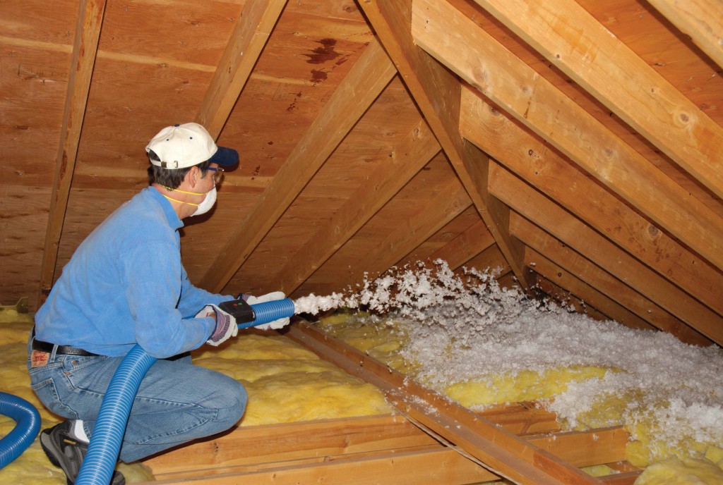 Home insulation contractor installing loose-full insulation in an attic.