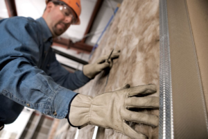 Technician installing batt insulation in a wall.