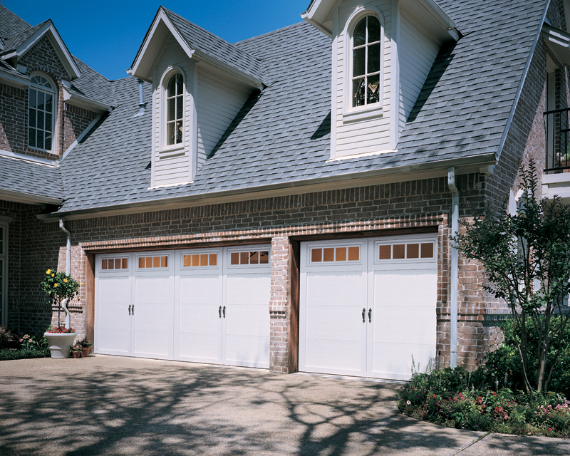 White three-car garage doors in brick home with two dormers above garage.
